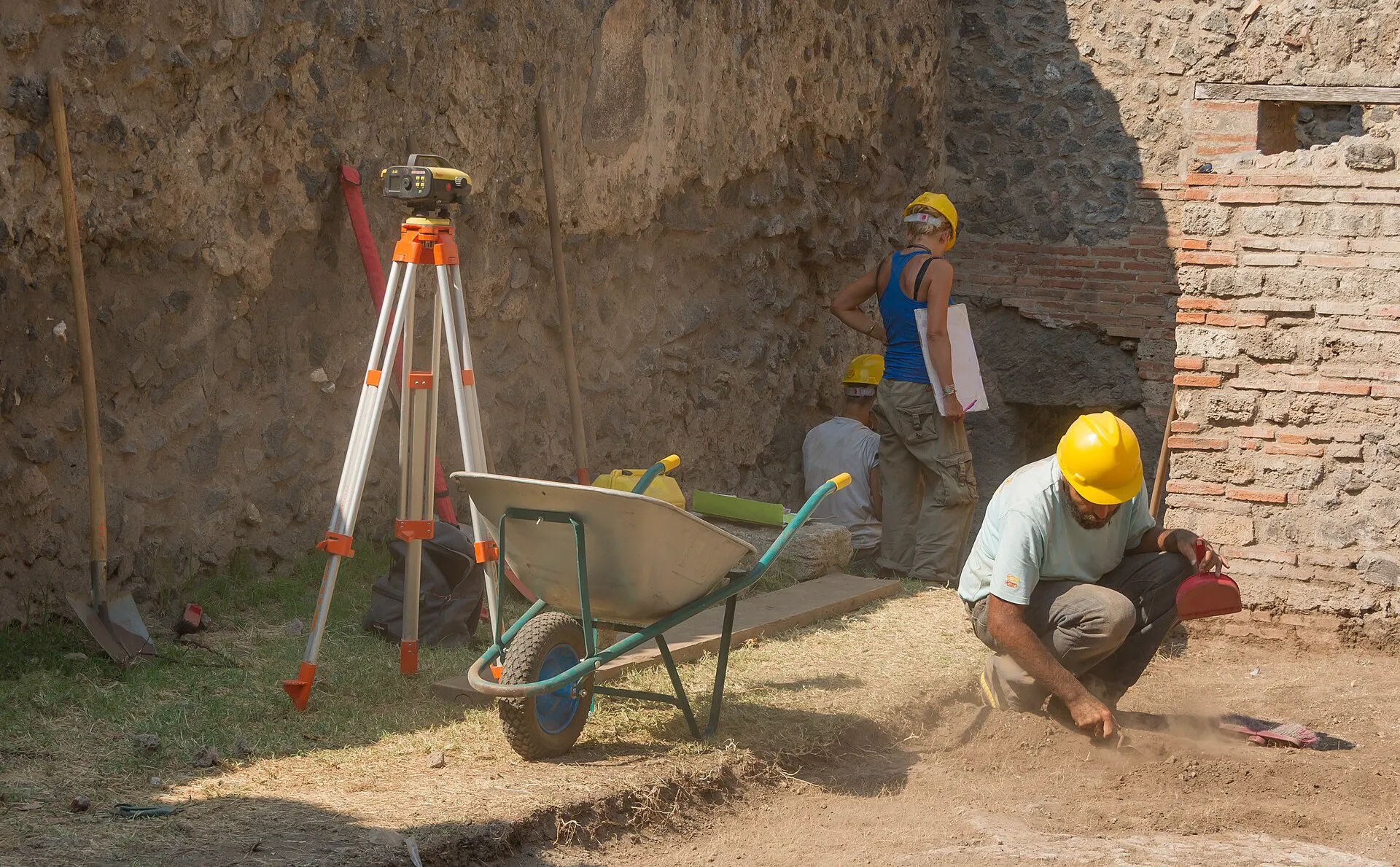 Surveyor at a tripod laying out points on an excavation