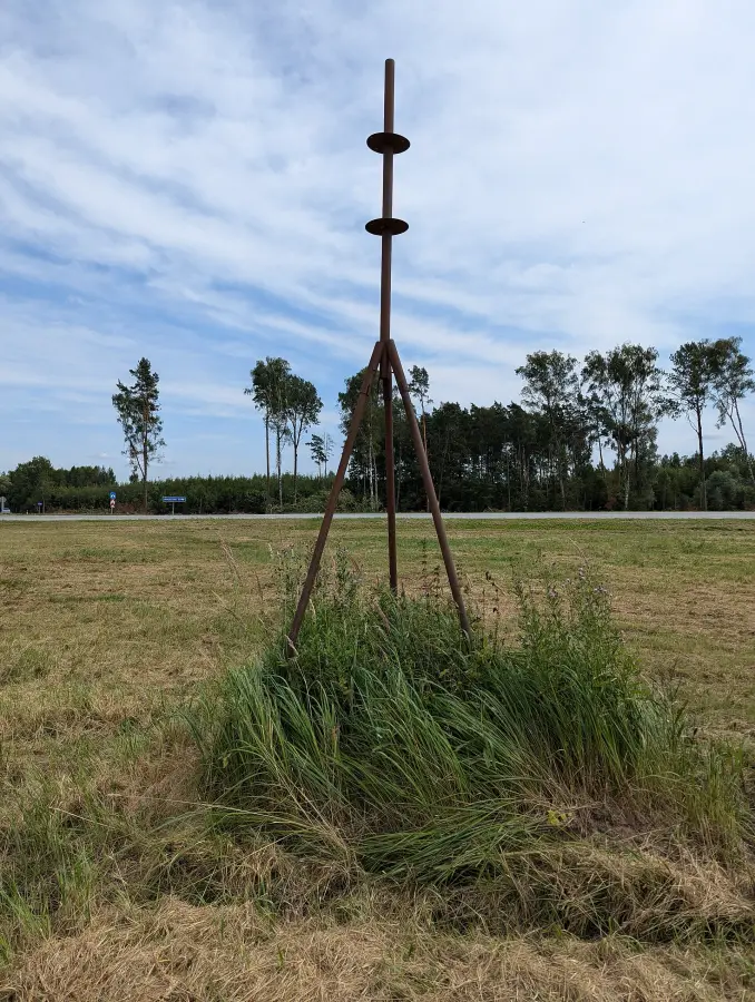 A tripod over a control point in an open field.