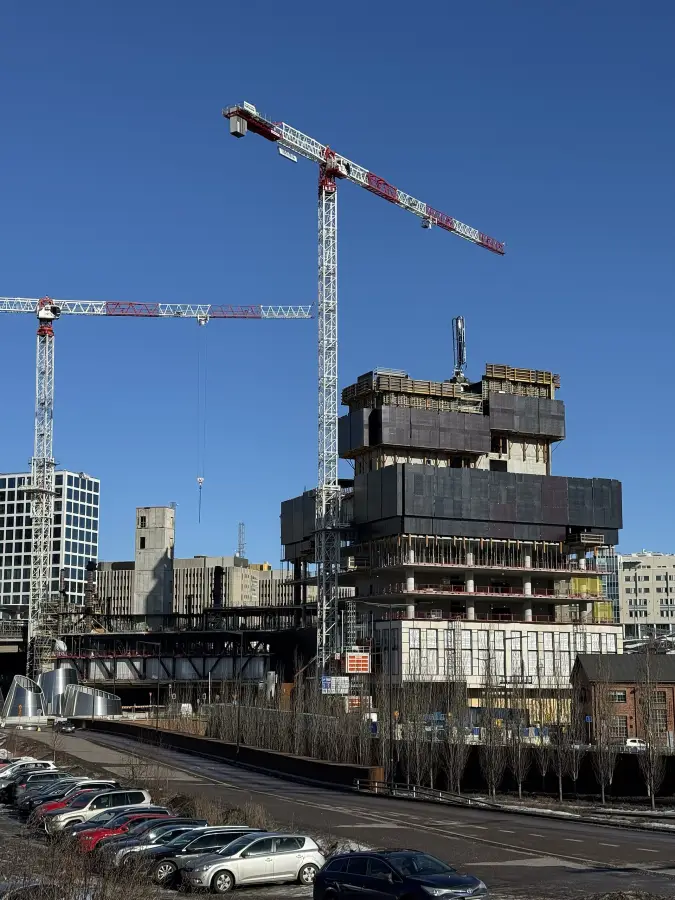 A high-rise frame climbing beside its tower crane.